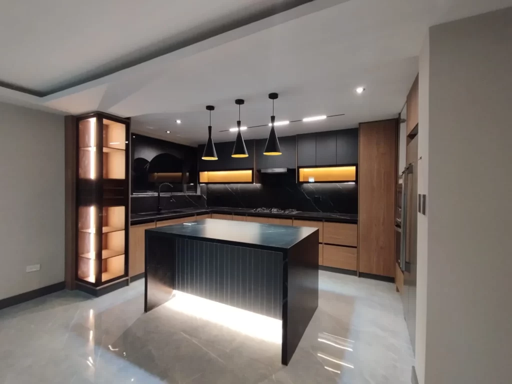 Cocina moderna con isla central iluminada, muebles en madera y acabados en negro